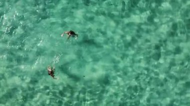 İki kadın güzel turkuaz okyanus suyunda yüzmekten zevk alır. Yaz tatilindeki dostların hava aracı görüntüsü.
