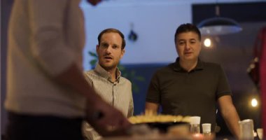 İki erkek, arkadaşlarıyla sıradan bir partide ya da akşamları iş ortamında eğlenirken dikkatle dinlerler..