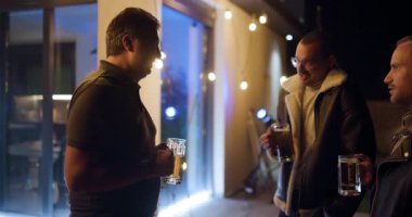 Üç arkadaş, rahat bir arka bahçede sohbet edip bira içerek gündelik bir akşamın tadını çıkarıyor..