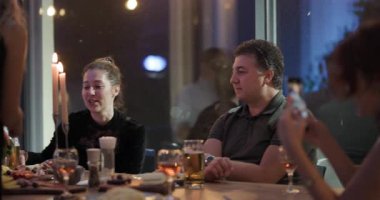 Arkadaşlar birlikte bir restoranda akşam yemeği yiyip mum ışığında sohbet ediyorlar..