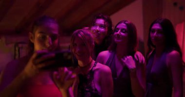 Partide beş arkadaş selfie çekiyor. Gülüyorlar, gülüyorlar ve birlikte olmaktan zevk alıyorlar. Eğlenceli bir anı yakalıyorlar..