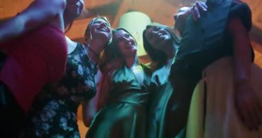 Arkadaşlar mezuniyeti renkli neon ışıklar altında bir ev partisinde kutluyorlar..