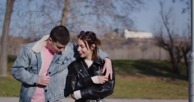 Güneşli bir günde genç bir çift parkta birlikte yürüyor, birlikte eğleniyor ve gülüyorlar..