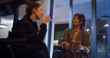 İki genç kadın, modaya uygun bir barda içki içip sohbet etmekten zevk alıyor. Şık giyinmişler ve canlı bir tartışma içindeler..