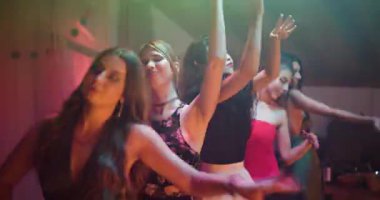 Bir grup arkadaş birlikte dans ediyor ve eğleniyorlar. Renkli ışıklandırma ve müzik eğlenceli bir atmosfer yaratır..