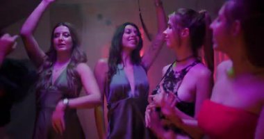 Beş genç kadın loş bir odada pembe ve yeşil ışıklarla dans ediyor. Mutlular ve gülümsüyorlar..