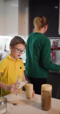Annesi arka planda bulaşıkları yıkarken genç bir çocuk dikkatlice bir bardağa süt döker. Birlikte sağlıklı ve lezzetli bir kahvaltı hazırlıyorlar..