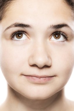 Yüksek çözünürlüklü yakın plan portresi, büyüleyici kahverengi gözlerine ve yumuşak tenine odaklanan genç bir kadının detaylı özelliklerini sergiliyor..