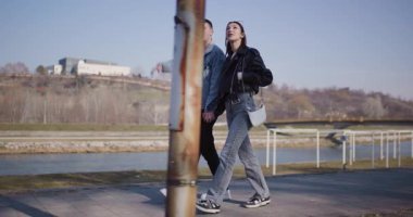 Genç bir çift güneşli bir günde el ele tutuşup nehir kenarında yürür. Dururlar, işaret ederler ve manzara hakkında konuşurlar..