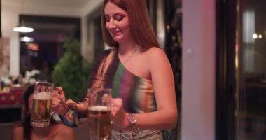 Arkadaşların gece birlikte doğum günü kutlaması. Parti şapkası takıyorlar, pasta yiyorlar ve bira içiyorlar. Kadeh kaldırır ve gülerler.