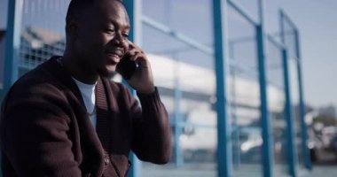 Parktaki bankta oturan genç bir adam hoş bir telefon görüşmesi sırasında konuşuyor ve gülüyor. Mutlu görünüyor ve sohbete dalmış..