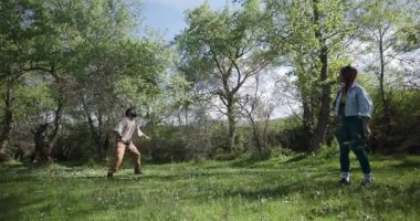 Doğada frizbi oynayan bir çift. Adam kadınlara frizbi atıyor. Yeşil yemyeşil ağaçlar mutlu çiftin etrafında.