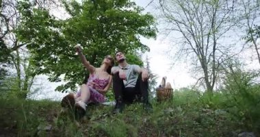 Çift, zengin doğayla çevrili romantik bir pikniğin tadını çıkarıyor. Sohbeti paylaşıyor ve sakin atmosfere hayran kalıyor..