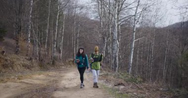 İki bayan arkadaş toprak yolda yürüyüş yapıyor, dağ manzarasının tadını çıkarıyorlar. Yol tarifi için bir harita ve telefona danışıyorlar. Macera ve dostluk ruhu gösteriyorlar..