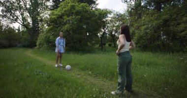 İki bayan arkadaş, yemyeşil bir parkta topla top oynuyorlar, açık havanın tadını çıkarıyorlar, ve doğaları gereği arkadaşlıklarını kucaklıyorlar..