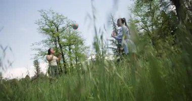 Güzel bir bahar gününde parkta yakalamaç oynayan iki genç kadın. Gülüyorlar ve güzel havanın tadını çıkarıyorlar. Park yeşil ve ağaçlar yemyeşil..