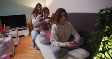 Bir grup arkadaş sıcak bir oturma odasında canlı bir pijama partisi veriyor. Rahat bir kanepeye otururlar, eğlenceli aktivitelere katılırlar ve kahkahaları paylaşırlar..