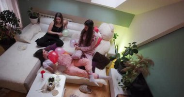 Arkadaşların birbirine eşlik ettiği, balonlarla oynadığı ve birlikte rahatlarken atıştırmalıklarla eğlendiği rahat bir oturma odasında eğlence dolu bir pijama partisi düzenlenir..