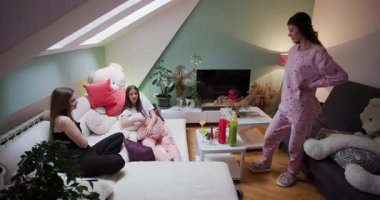 Sıcak bir oturma odasında, arkadaşlar pijama partisi için toplanır, hikayelerini ve kahkahalarını paylaşarak atıştırmalık ve içeceklerin tadını çıkarırlar. Atmosfer canlı ve rahat..