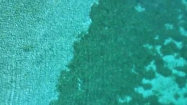 Ohri Gölü 'ndeki kristal berrak turkuaz suyun havadan görünüşü. Sığ alan, deniz yatağı dokusuyla daha derin kısımlarla birleşiyor. Manzaralı yaz seyahati.