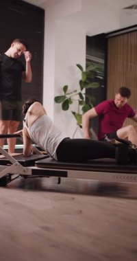 Katılımcılar şık bir stüdyoda pilates seansına katılıyorlar. Eğitmen, teknik ve kontrol üzerine yoğunlaşırken onlara çeşitli yenilikçi alıştırmalarda rehberlik eder..