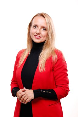 Profesyonel bir kadın, çarpık kolları ve çarpıcı kırmızı bir ceket giyerken parlak bir gülümseme ile kendine güvenerek ayakta durur. Ofis ortamında karizma ve liderlik yayıyor..