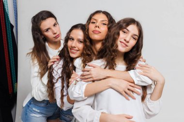 Neşeli ifadeleri olan dört genç kadın bir arkadaşlık ve yakınlık anını paylaşıyor. Tarafsız bir ortamda günlük beyaz gömlekler giyiyorlar..
