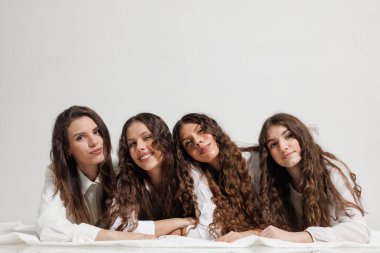 Uzun saçlı, yakından poz veren dört genç kadından oluşan bir grup. Hafif bir arka planda gülümseyerek dostluk, birliktelik ve neşe temalarını dile getiriyorlar..