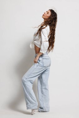 Modern modayı rahat bir pozda sergileyen şık bir kot ve zarif estetik karışımını vurgulayan, stüdyoya zamansız çağdaş bir görünümle güven saçan şık bir birey.