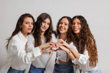 Gündelik giysiler içinde dört neşeli genç kadından oluşan bir grup elleriyle bir kalp şekli yaratarak birlik, dostluk ve neşeyi sembolize ediyor..