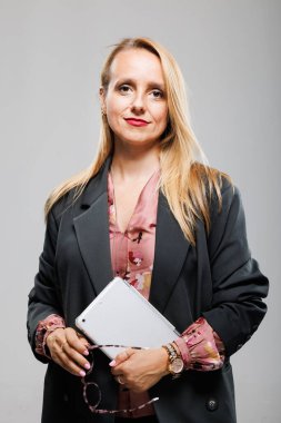 Bir iş kadını, modern ofis ortamında poz verirken elinde tablet olan şık ve profesyonelliğin bir karışımını yansıtan şık bir kıyafete güvenir..