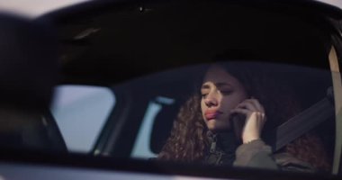 Dişlerinde diş teli olan neşeli genç bir kadın akıllı telefonunu arabada kullanıyor, mutluluk ve bağlantı yayıyor..