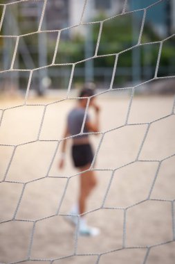 Kumlu bir arazide bir kadın ağ vasıtasıyla görüldü, spor yapıyor, açık havada ve odaklanıyor..