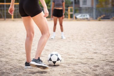 Sporcular kum plajı voleybol sahasında antrenman yapıyor, top kontrolü ve takım çalışmasına odaklanıyor..