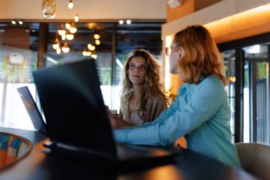 İki iş kadını modern bir ofiste şık bir masada oturuyorlar..