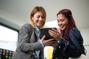 İki meslektaş, olumlu enerji ve profesyonellik alışverişinde bulunurken bir tabletin etrafında toplandılar..