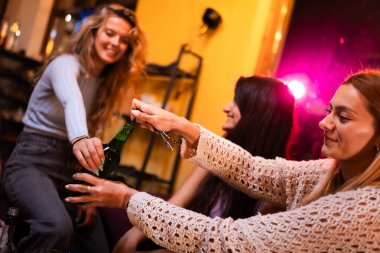 Üç arkadaş neşeli bir kafede neşeli bir anı paylaşıyor, içkilerle kaynaşıyor ve canlı sohbetler kuruyor, sıcaklık, bağlantı ve dostluk ortamı yaratıyor..