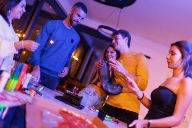 Genç insanlar, renkli dekorasyonlar ve neşeli anlarda vurgulanan canlı bir doğum günü kutlaması sırasında kahkaha ve mutluluğu paylaşıyorlar..