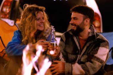 İki arkadaş kamp ateşinin yanında sıcak bir akşamın tadını çıkarıyor. Bir kamp alanında yıldızlı gökyüzünün altında kahkahalarını ve içkilerini paylaşıyorlar. Alevler mutlu yüzlerini aydınlatıyor..