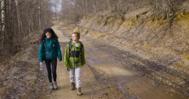İki bayan arkadaş, sakin bir ormanla çevrili toprak bir yolda yürüyüş yapmaktan zevk alıyor. Yürürler ve konuşurlar, barışçıl atmosferin ve birbirlerinin arkadaşlığının tadını çıkarırlar..