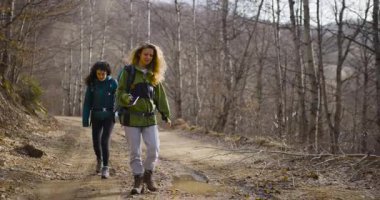 İki bayan arkadaş, doğanın huzurlu güzelliğiyle çevrili sakin bir dağ yolunda sakin bir yürüyüş yapıyorlar..