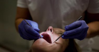 Bir diş hekimi hastasının dişlerini yakından inceler ve tedavi eder. Detaylı çalışma, klinik bir ortamda hassasiyet ve bakım göstermektedir..