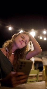 Canlı bir restoranda gece boyunca çekilen neşeli bir an. Telefonuyla selfie çekerken gülümseyen kişi, canlı atmosferin ve iyi bir arkadaşlığın tadını çıkarıyor..