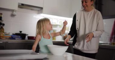 Anne ve kızı mutfakta birlikte yemek hazırlıyorlar. Aile kaliteli zaman geçirir ve yemek pişirme becerilerini öğrenir..