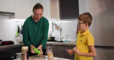 Bir anne ve oğul modern mutfaklarında tatlı bir ziyafet hazırlıyorlar. Kalıplara bir hamuru döküyorlar, sevgi dolu bir aile anını gösteriyorlar..