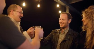 Arkadaşlar geceleri terasta içki içip sohbet etmekten zevk alıyorlar. Sıcak sicim ışıkları rahat bir atmosfer yaratır..