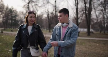 Güneşli bir günde genç bir çift el ele tutuşup parkta yürür. Aynı çiçeği paylaşıyorlar ve birlikte gülüyorlar..