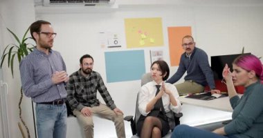 İş dünyasından profesyoneller bir ofisteki masanın etrafında tartışırlar. Fikirlerini paylaşıyorlar ve projeleri hakkında güncelleme sağlıyorlar. Ayar parlak ve işbirlikçi..