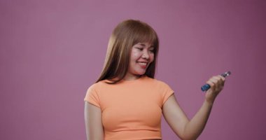 Odaklanmış Asyalı kadın elleri üzerinde çalışıyor. Pembe bir arka planda metal bir el tutuşu kullanıyor. Günlük fitness rutininin yakalanması.