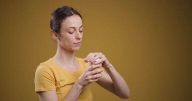 Genç bir kadının beyaz bir bardaktan nazikçe yudumladığı sakin bir an. Gözleri hardal renginde bir arka planda kapalı..